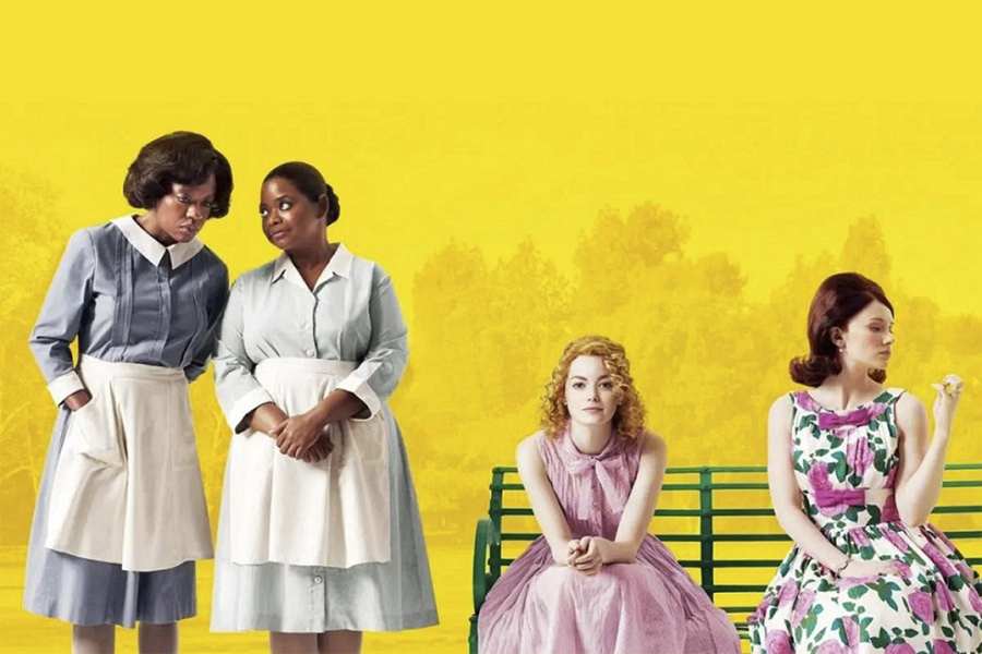 Duas mulheres negras em pé, com uniformes de domésticas ao lado de duas mulheres brancas sentadas em banco de praça em um fundo amarelo.